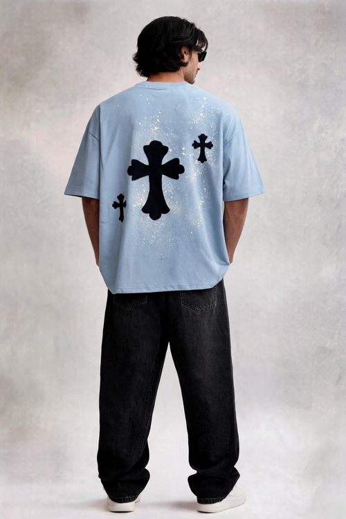Person wearing a light blue t-shirt with black cross designs on the back against a plain background