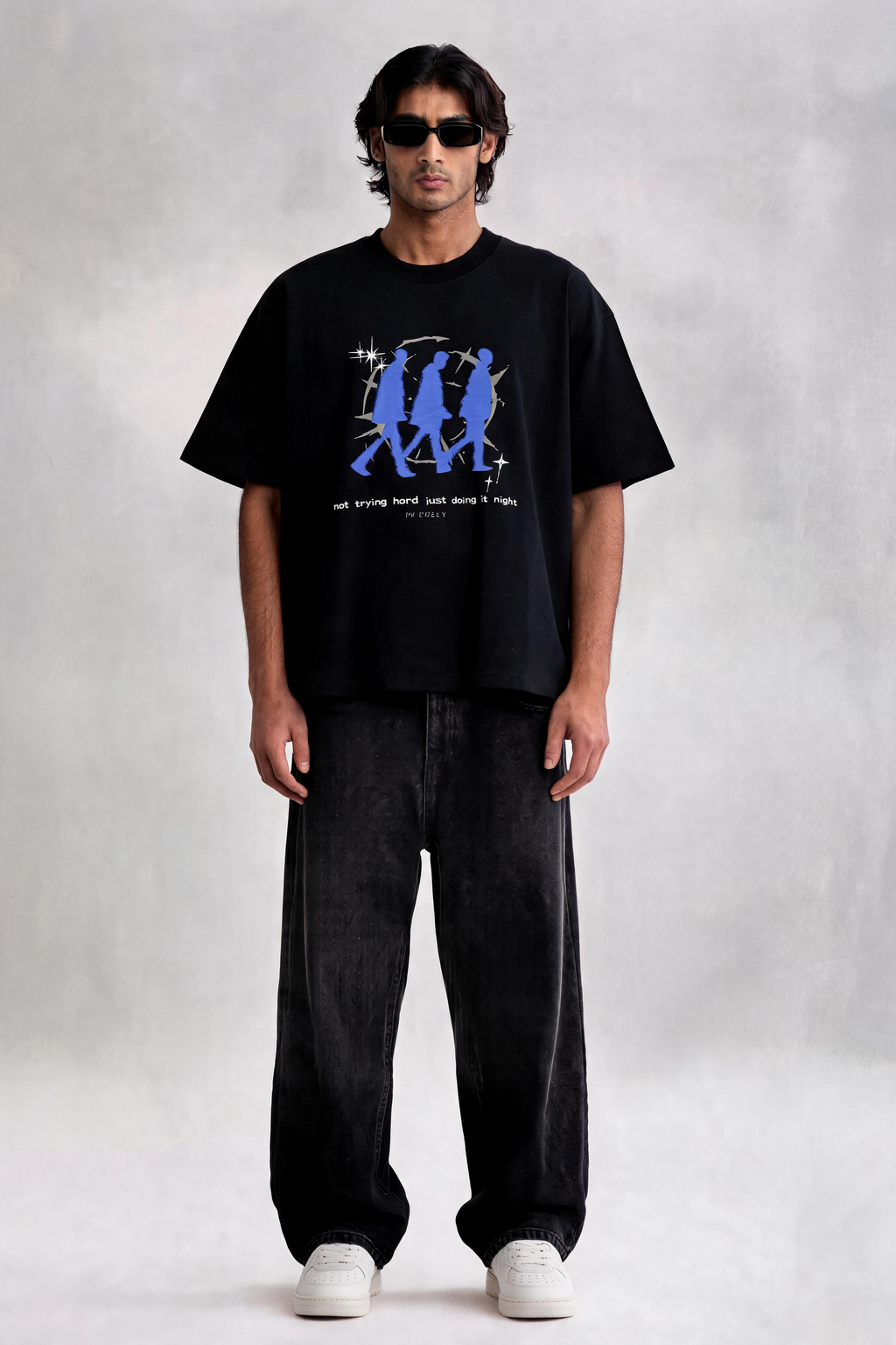 Man wearing a black t-shirt with a blue graphic and text, standing against a plain background