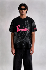 Person wearing a black t-shirt with pink text and dark pants on a light gray background