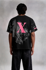 Person wearing a black t-shirt with a pink 'X' on the back against a gray background