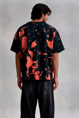 Person wearing a black and red abstract patterned shirt with black pants on a light gray background