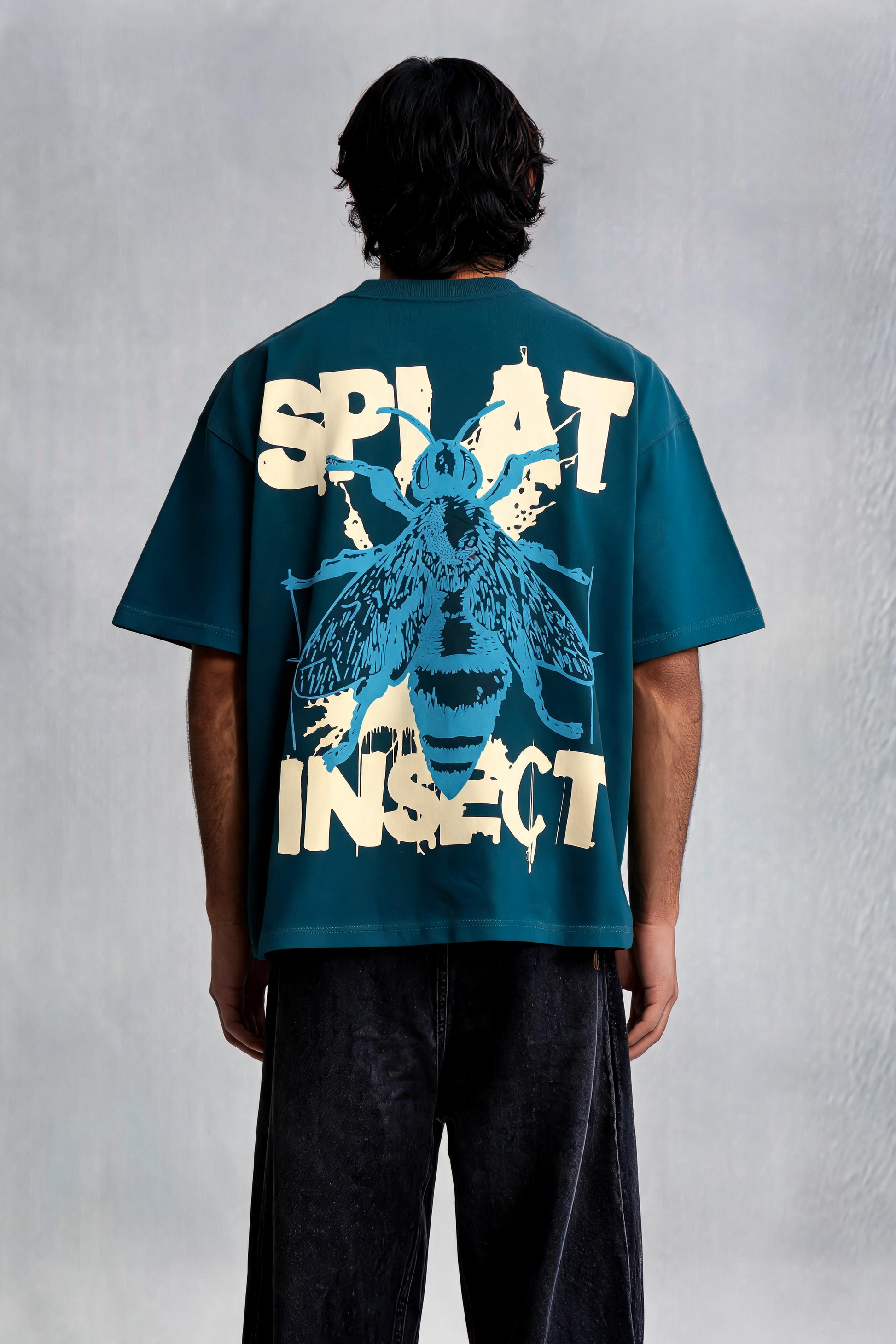 Person wearing a teal t-shirt with a graphic design on the back, standing against a plain background