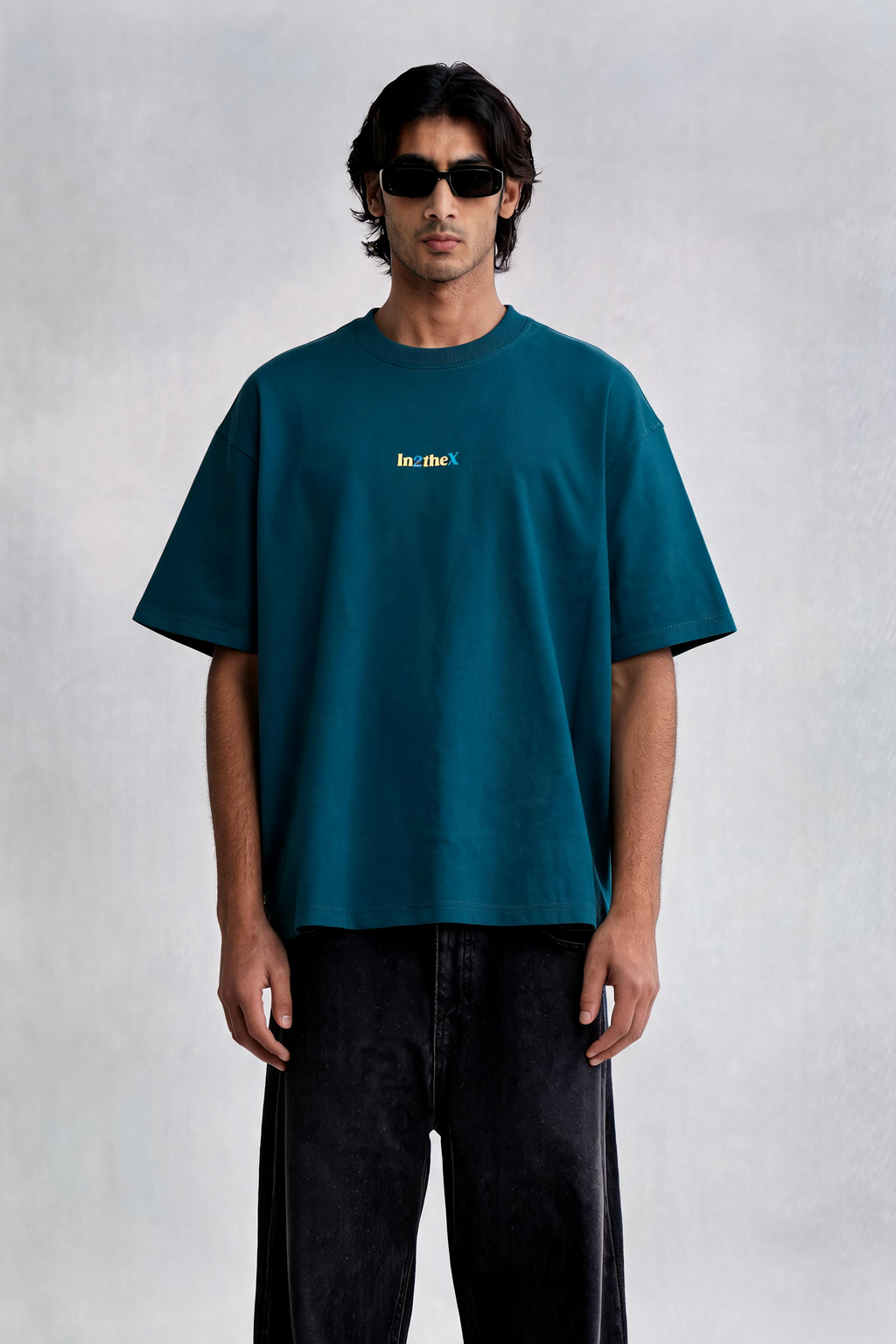 Man wearing a teal t-shirt and black pants on a white background