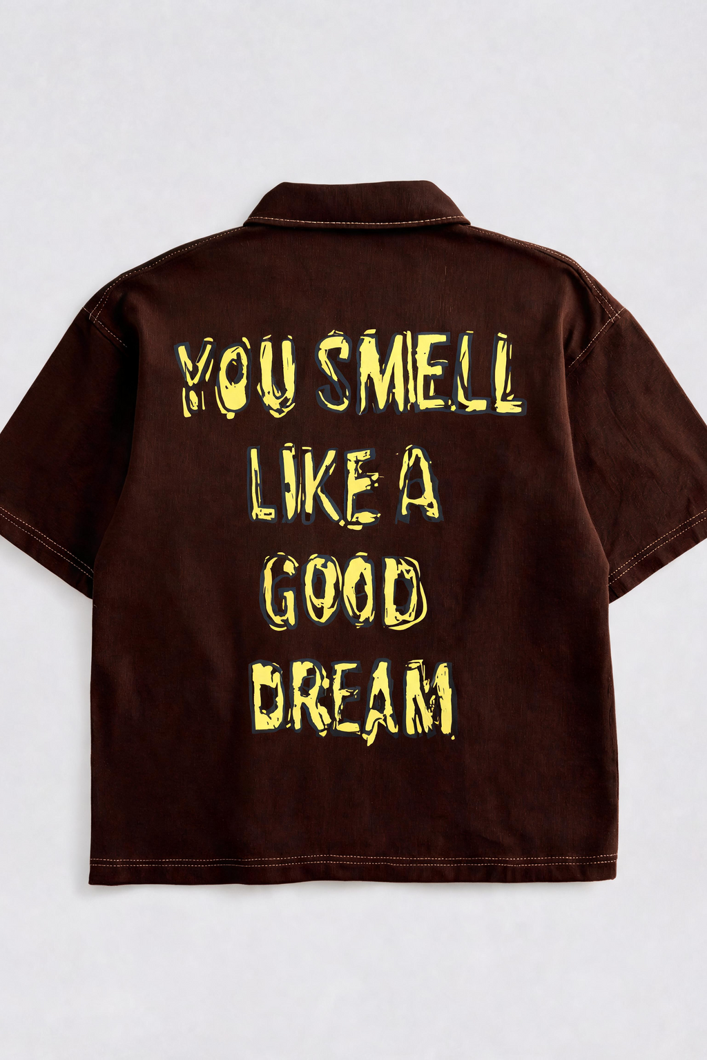 Brown shirt with yellow text 'YOU SMELL LIKE A GOOD DREAM' on a white background