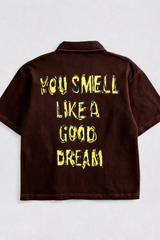 Brown shirt with yellow text 'YOU SMELL LIKE A GOOD DREAM' on a white background