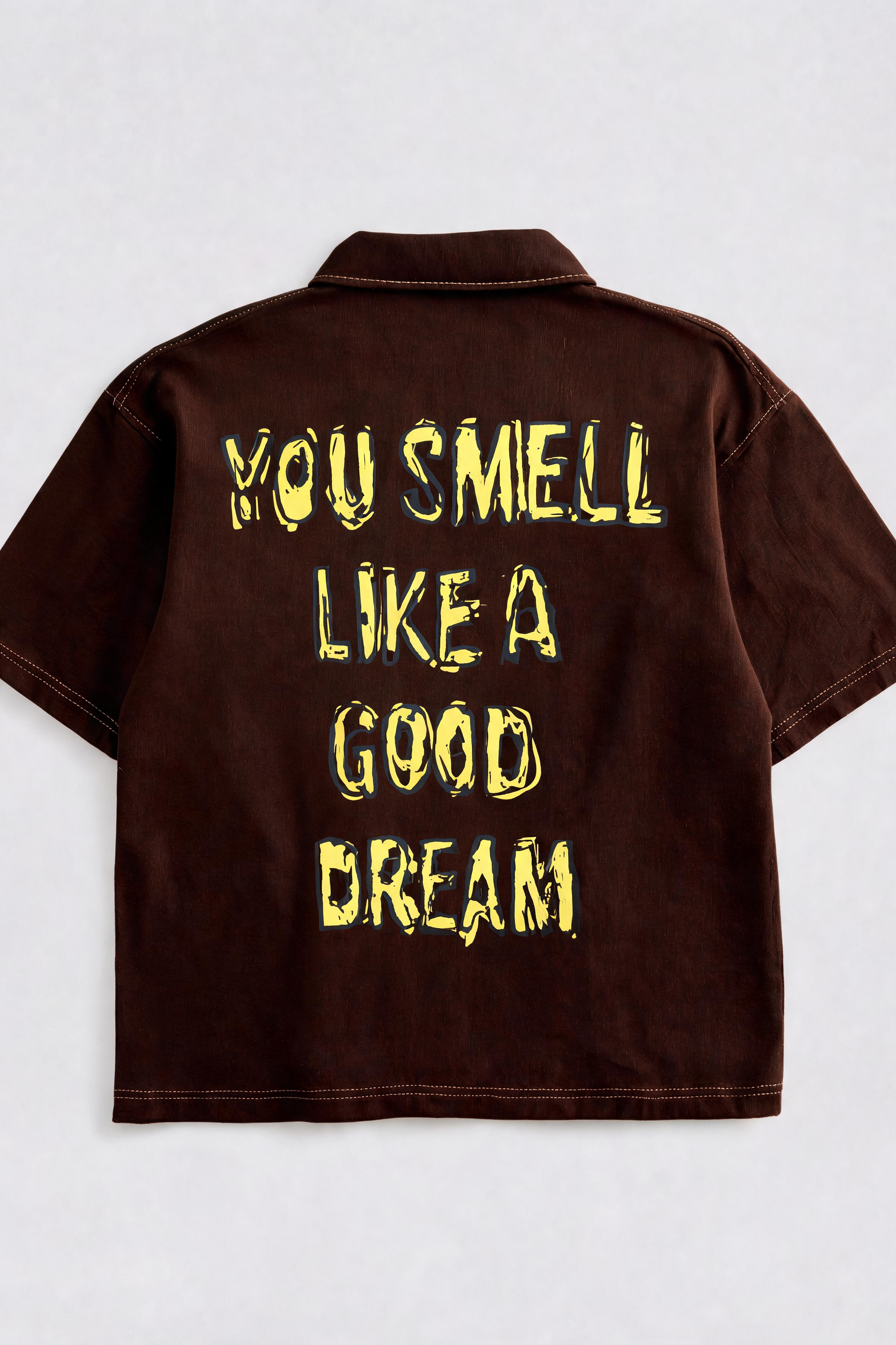 Brown shirt with yellow text 'YOU SMELL LIKE A GOOD DREAM' on a white background