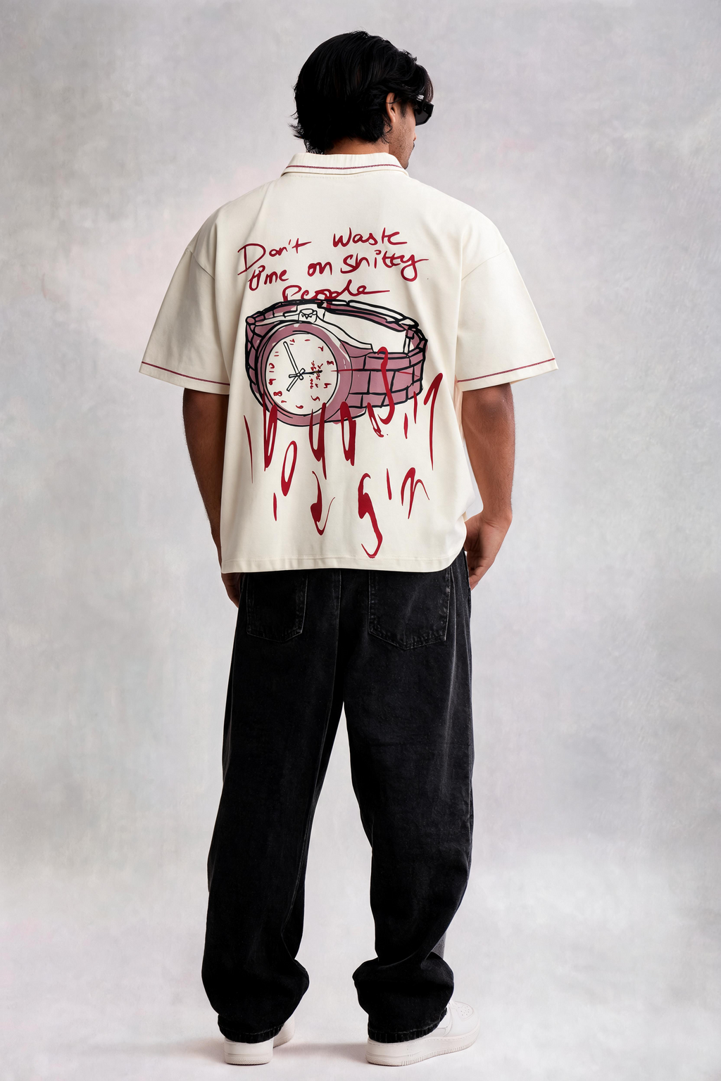Person wearing a white shirt with red graphics and text, standing against a plain background