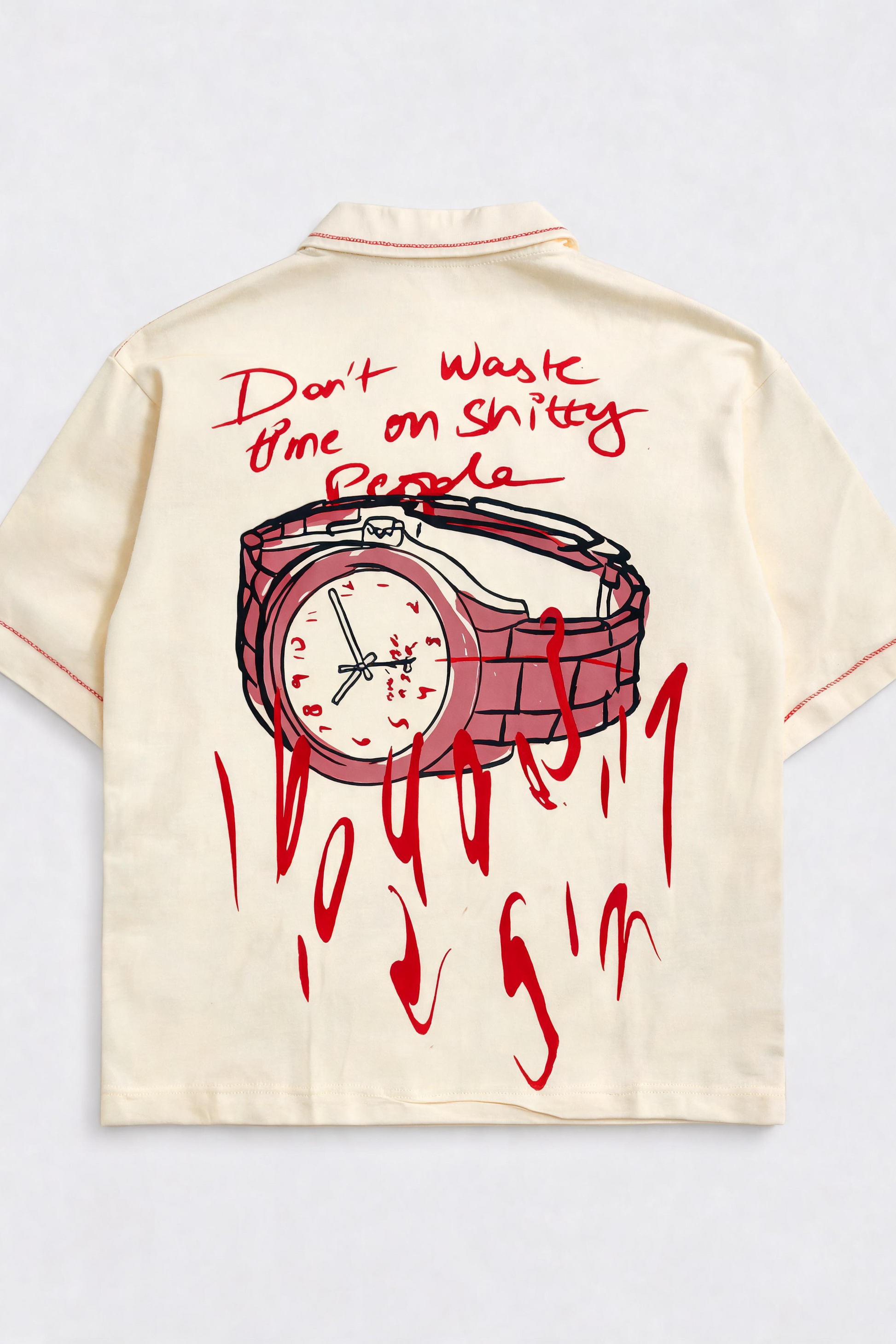 Beige shirt with red graphic of a watch and text on a light gray background