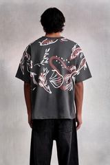 Person wearing a dark gray t-shirt with red and white floral patterns on a plain background